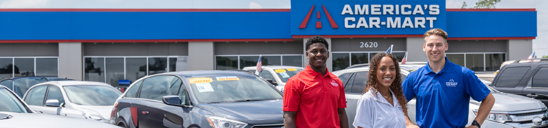 Three employees standing in front of cars at America's Car-Mart